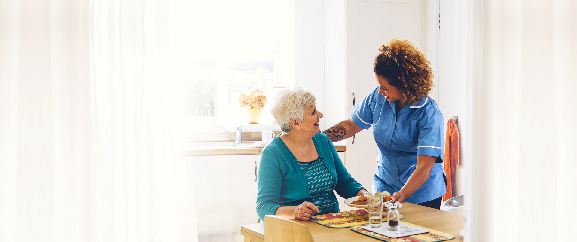 caregiver serving meal to a senior woman
